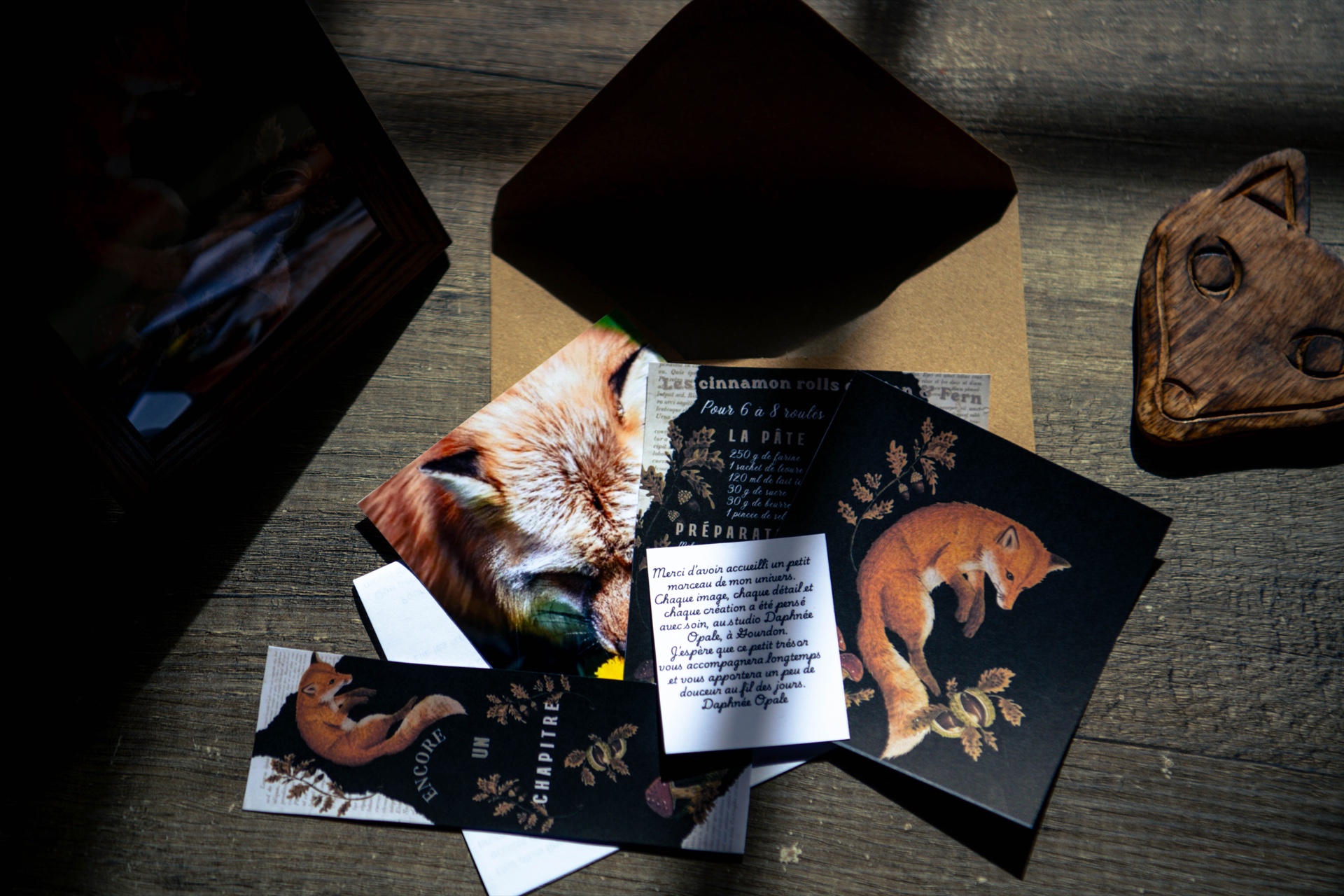Enveloppe et éléments illustrés du Courrier du Sous-Bois disposés sur une table sombre
